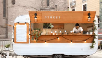 ristoratore sorridente affacciato dal suo food truck roulotte