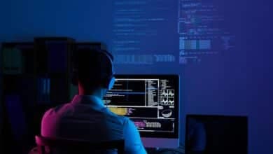 programmatore informatico lavora al computer in una stanza con luce blu