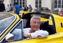 Uomo di mezza età di successo guida una ferrari gialla