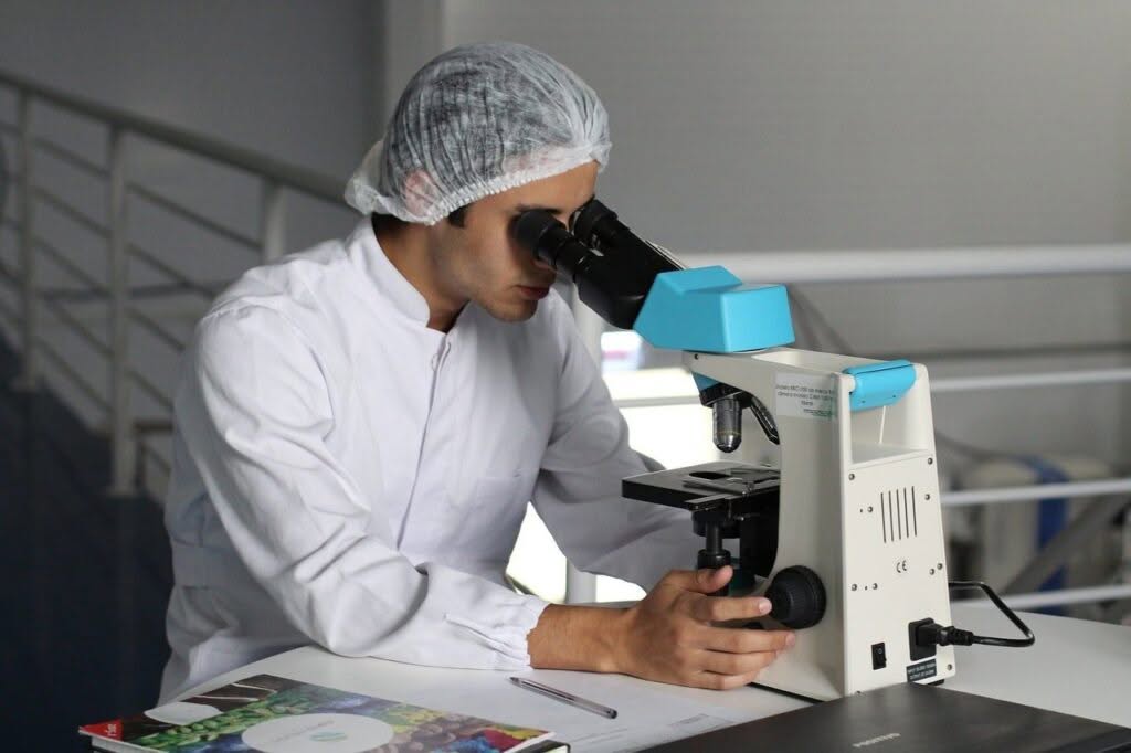 Ricercatore in camice bianco guarda attraverso un microscopio