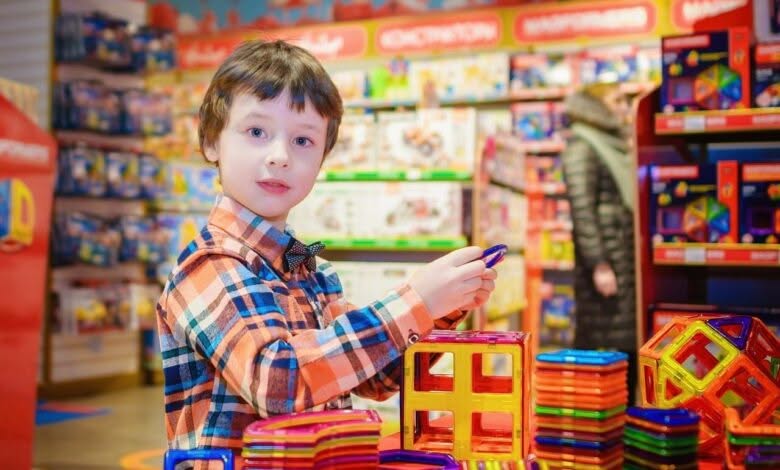 Bambino con capelli neri e camicia di flanella gioca con delle costruzioni colorate
